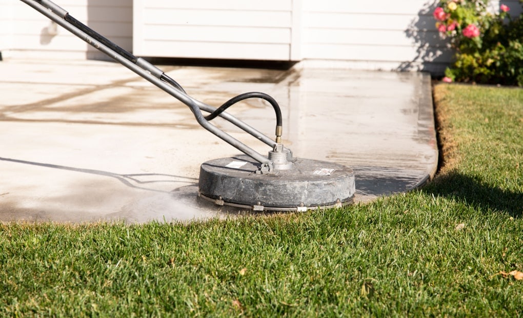 A LevelUp technician power washing a concrete driveway