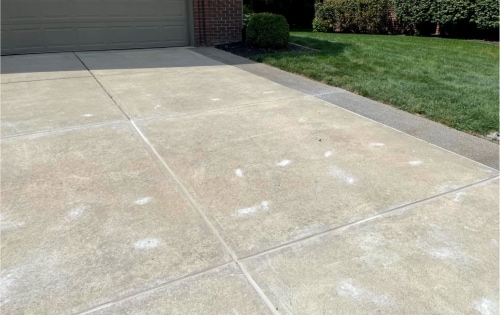 A cracked and uneven driveway filled with concrete repair sealant in Indianapolis.