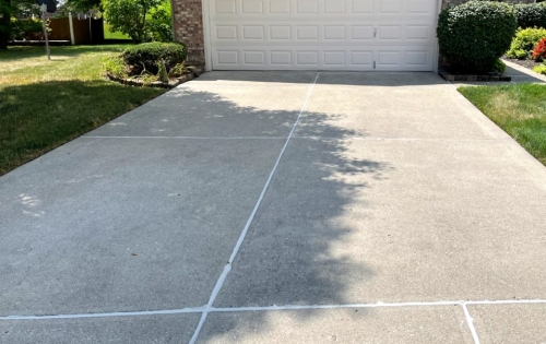 A newly repaired concrete driveway with filled cracks
