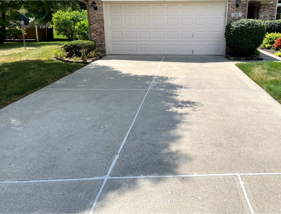 A newly repaired concrete driveway with filled cracks