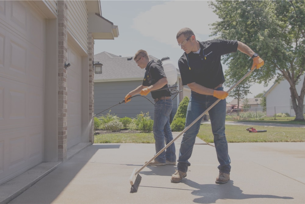 Two LevelUp techicians applying a concrete sealant to driveway
